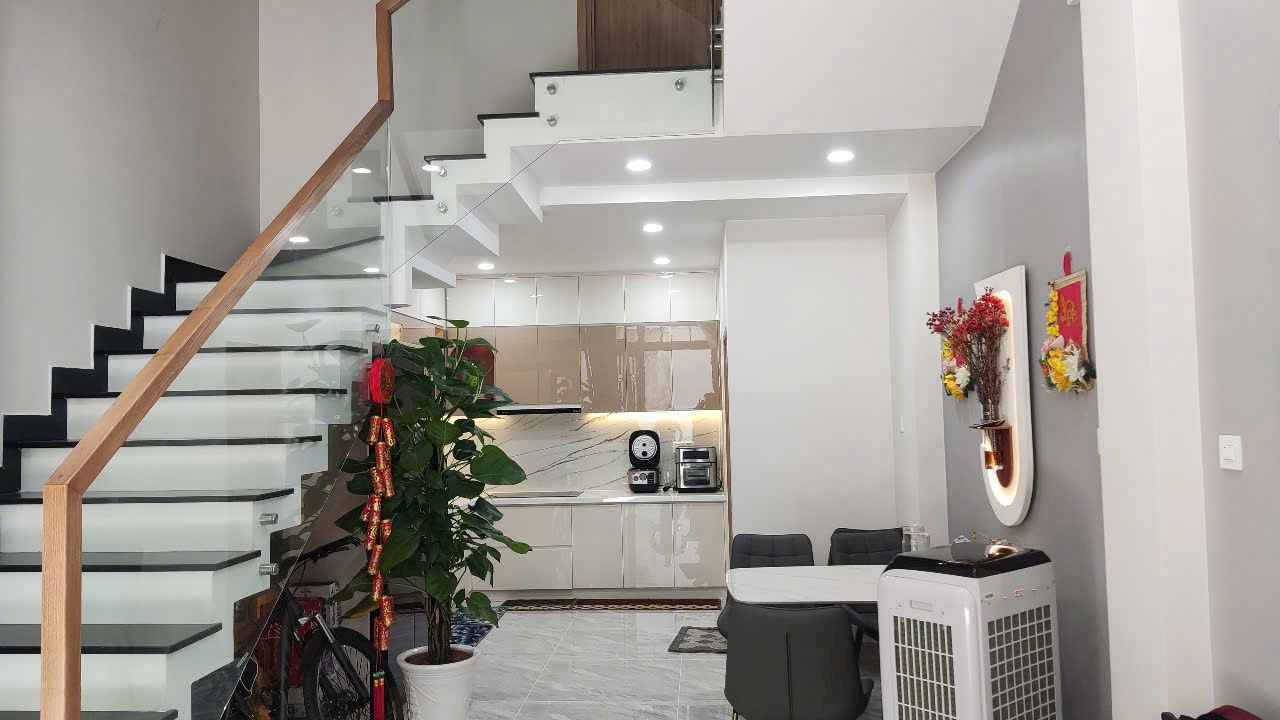 Bếp và cầu thang tầng trệt, nhà phố mặt tiền xanh rêu do Khả Văn thực hiện
